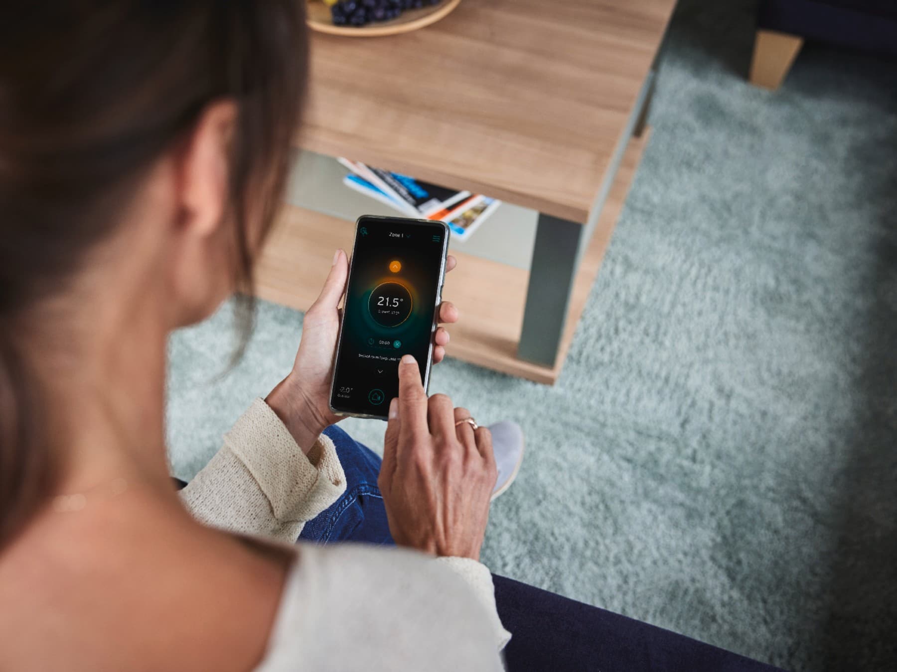 Kobieta dostosowująca ustawienia systemu smart home za pomocą smartfona.