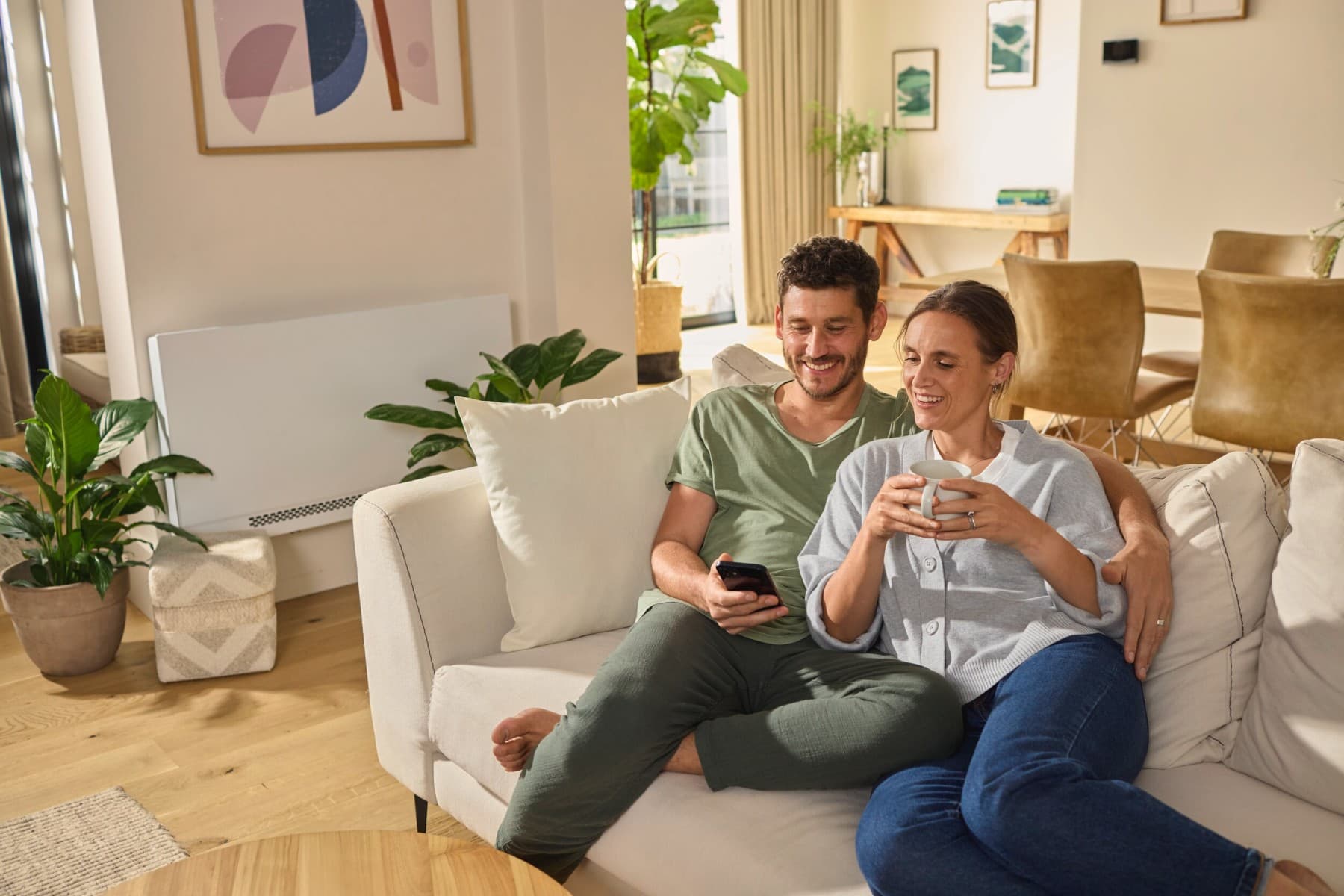 Para siedząca na sofie i patrząca na smartfon